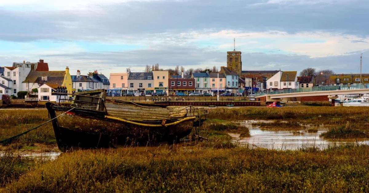 Shoreham-by-Sea waterfront with colourful harbour houses, the church tower and a traditional wooden boat on the Adur estuary